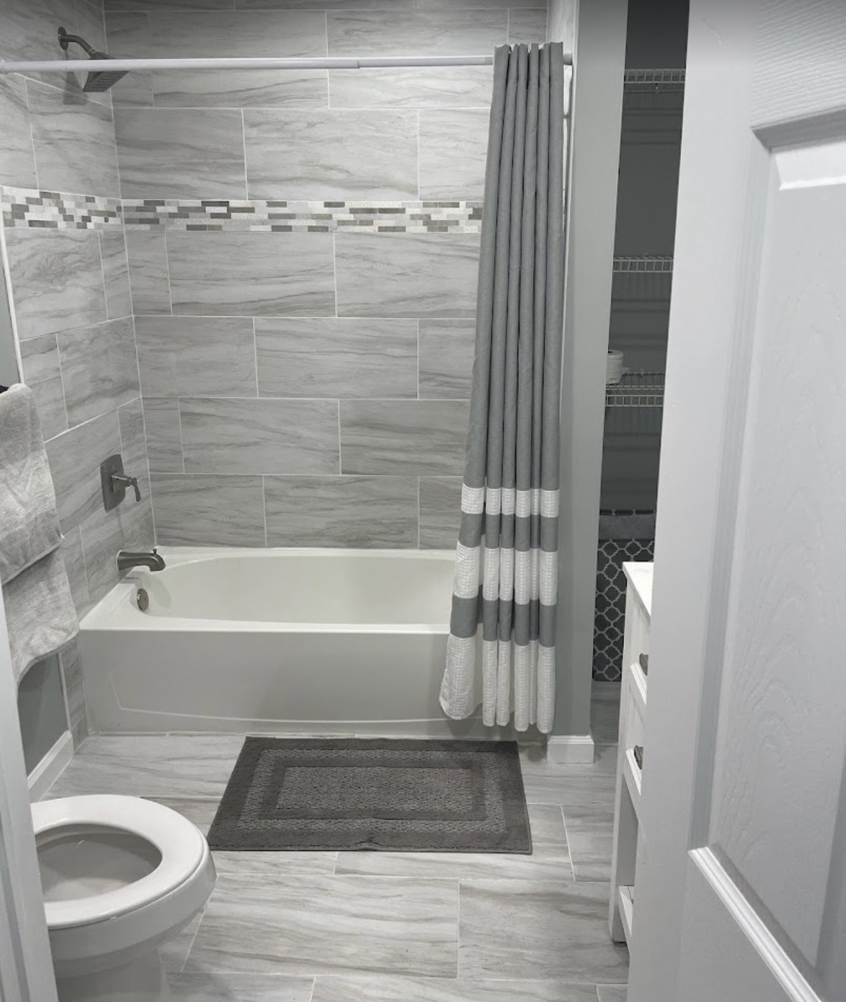 Stone-look tile tub-and-shower combo with mosaic accent band